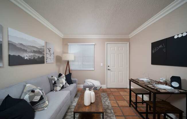 Living room with crown molding and Saltillo tile floors in model unit at the Atrium Apartments in San Diego, California.