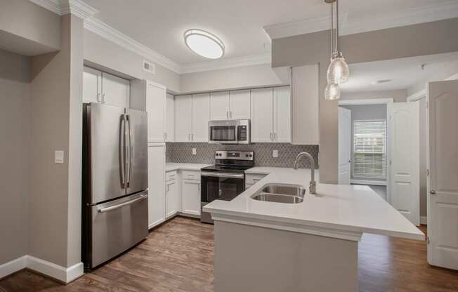 a white kitchen with stainless steel appliances and a white counter top