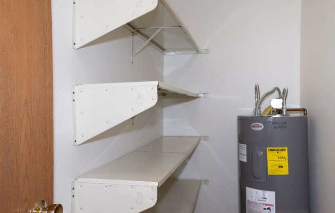 a small pantry with white shelving and a water heater. Fargo, ND Pacific South Apartments