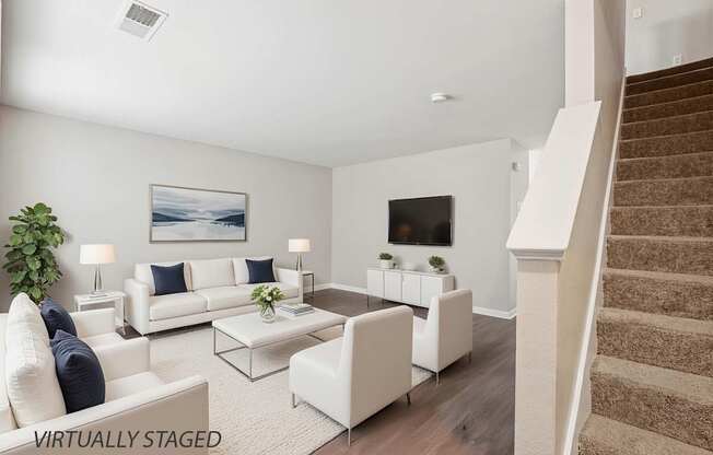 A living room with a staircase on the right side.