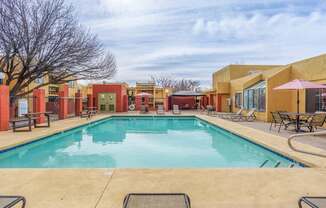 A large outdoor swimming pool surrounded by lounge chairs and umbrellas.