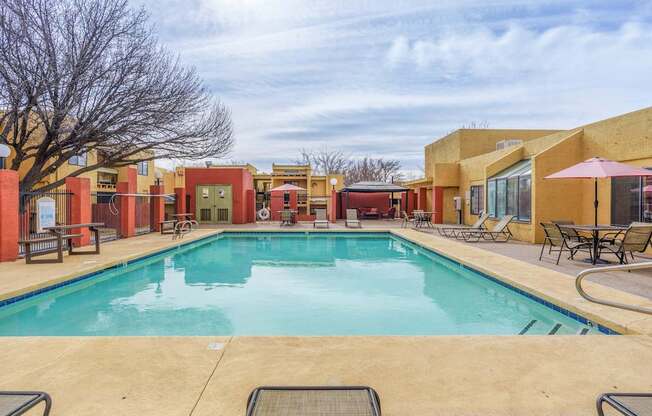 A large outdoor swimming pool surrounded by lounge chairs and umbrellas.