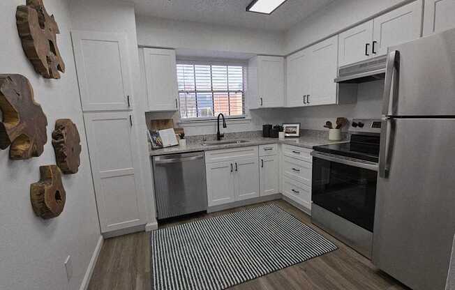 A kitchen with white cabinets and a refrigerator.