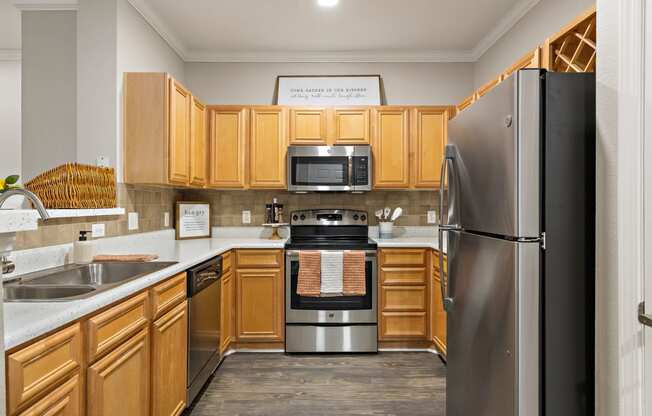 a kitchen with wooden cabinets and stainless steel appliances at The Verandah, Austin, TX