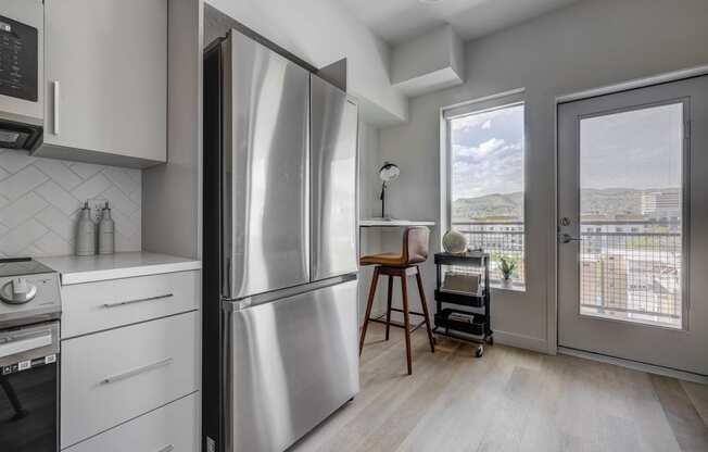 a kitchen with a refrigerator and a door to a balcony