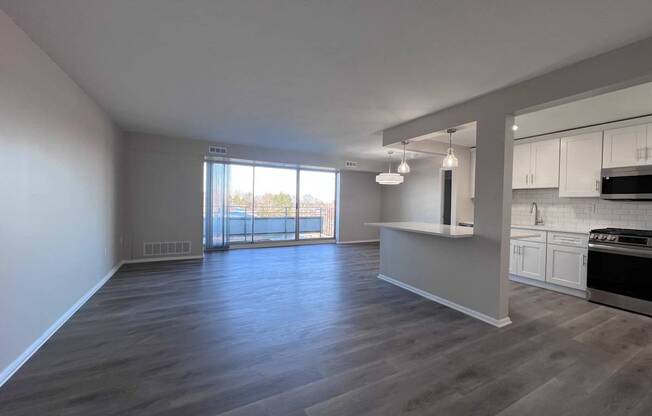 an empty living room and kitchen with wood flooring