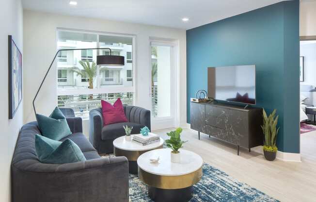 Pet-Friendly Apartments in Woodland Hills, CA - The Q Variel - Living Room with Luxury Vinyl Plank Flooring, a Large Window, and Access to a Private Patio/Balcony