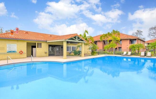 A swimming pool in front of a building with a red roof.