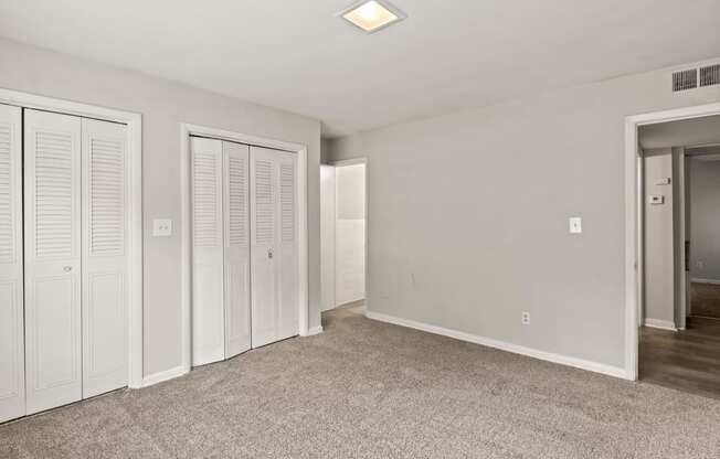 a bedroom with white closets and a carpeted floor