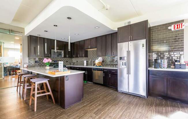 A kitchen with a refrigerator, stove, and bar stools.