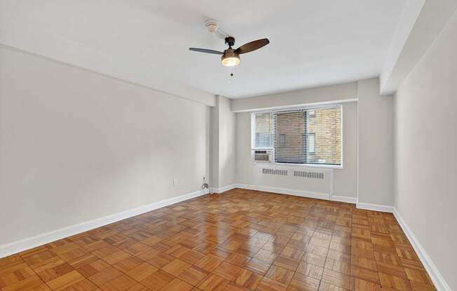 A room with a ceiling fan and wooden flooring.