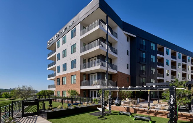 A modern apartment building with a fitness area in the front yard.