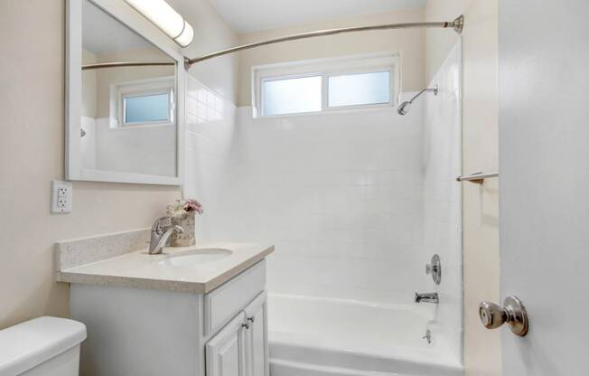 a white bathroom with a shower and a sink