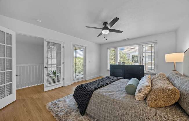 A bedroom with a bed, pillows, and a ceiling fan.