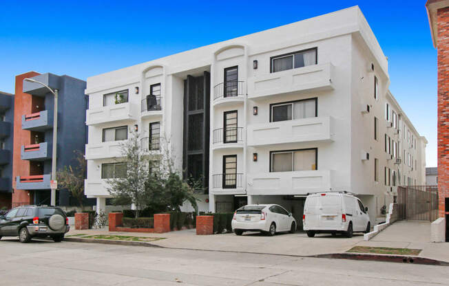 a white apartment building with cars parked in front of it