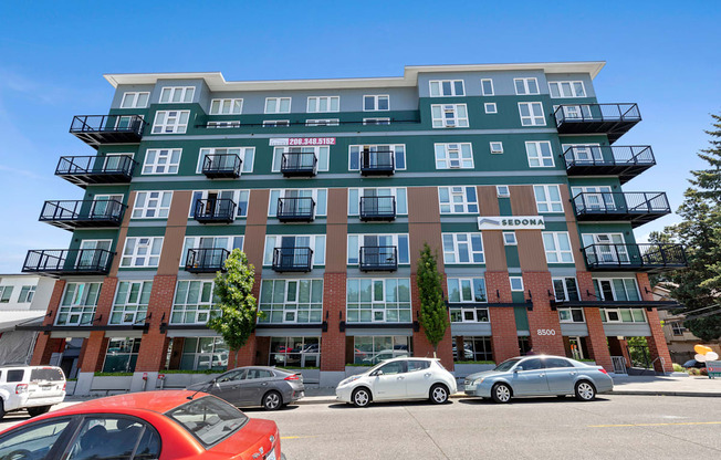 an image of the large property building with cars parked in front of it  at Sedona Apartments, Seattle, WA