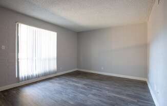 an empty living room with wood floors and a window