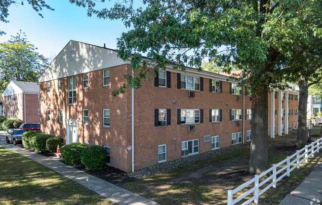 A red brick building with a white fence in front.
