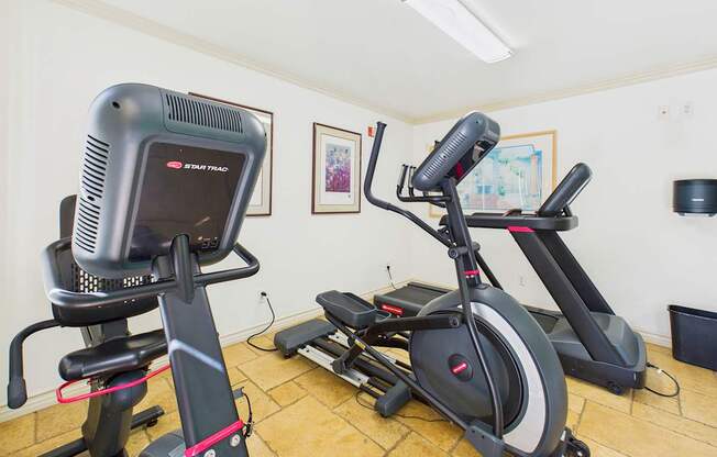 A room with a treadmill and a stationary bike.