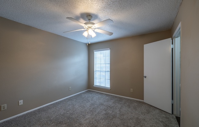 A room with a ceiling fan and a window with blinds.
