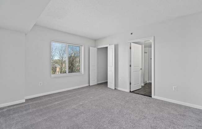 an empty living room with white walls and a window