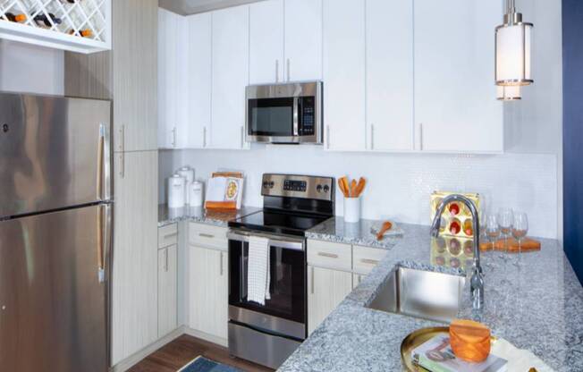 A modern kitchen with a granite countertop and stainless steel appliances.