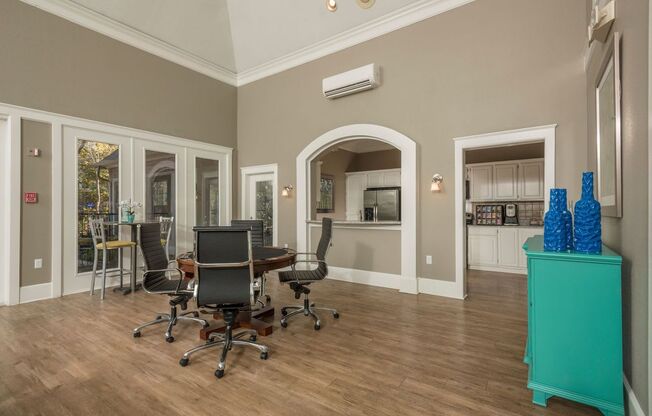 a conference room with a table and chairs and a kitchen in the background