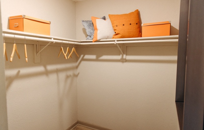 a walk in closet with a shelf with pillows and hangers