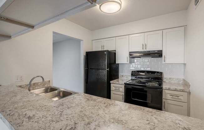 A kitchen with granite countertops and white cabinets.