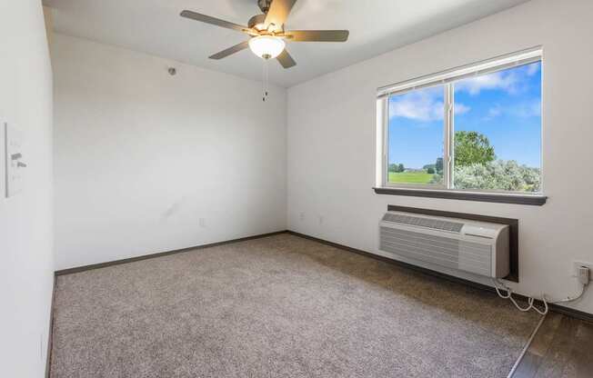 A room with a ceiling fan and a window showing a view of the outside.