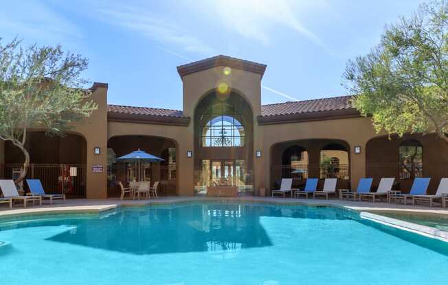 a resort style swimming pool with lounge chairs and umbrellas