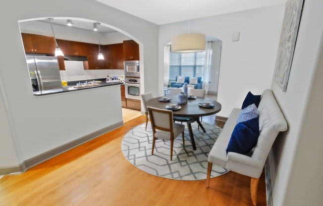 a dining area with a table and chairs and a kitchen in the background