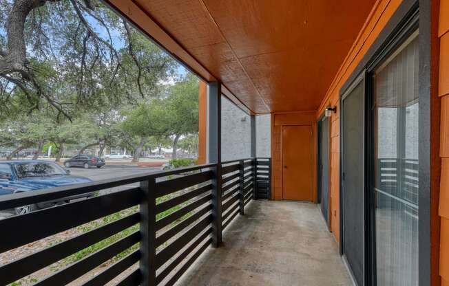 a long balcony with black railing and an orange door