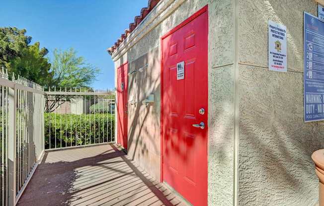 A red door is on the left side of a building with a sign on the right side.