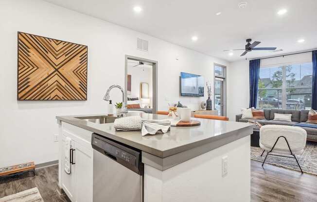 a kitchen with a sink and a dishwasher next to a living room