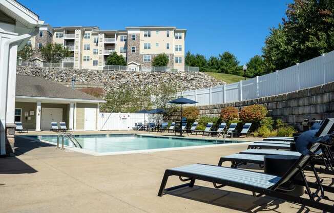 a swimming pool with lounge chairs and a building in the background