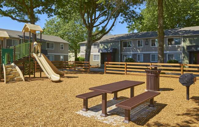 a playground with a slide and a picnic table in front of apartments at Woodhaven, Everett, Washington