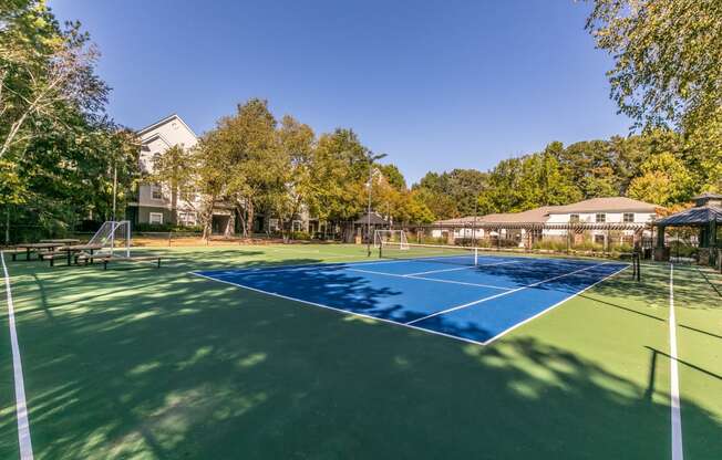 a tennis court with trees and a house in the background at Deerfield Village, Alpharetta, Georgia