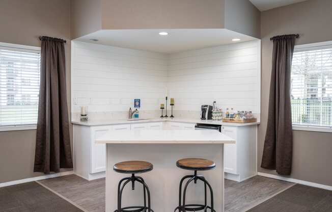 a kitchen with a bar and two stools in front of a counter