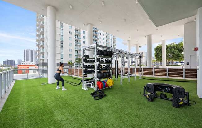 A woman is exercising in a gym with a green floor and white pillars.