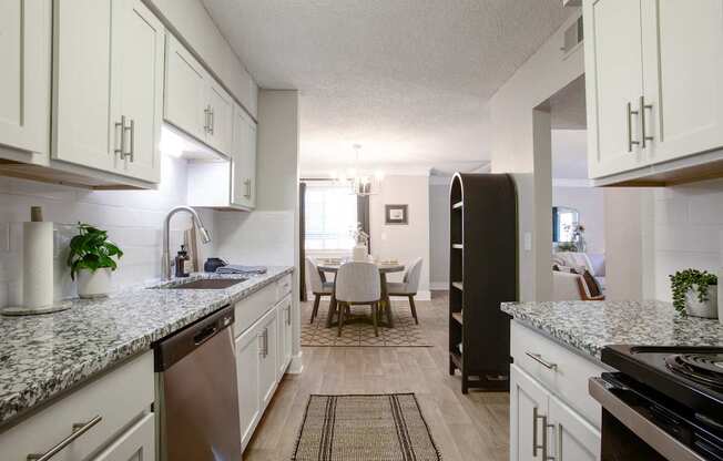 A kitchen with white cabinets and a marble countertop.