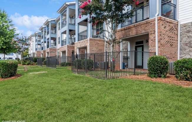 our apartments at the district feature a lush green lawn and a wrought iron fence