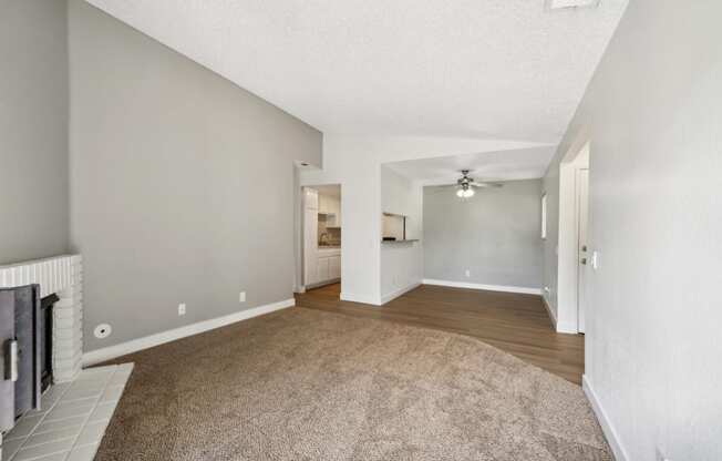 the spacious living room and dining room with white walls and carpeting