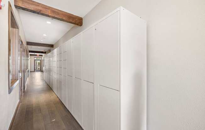 a long row of white cabinets in a hallway with wood floors