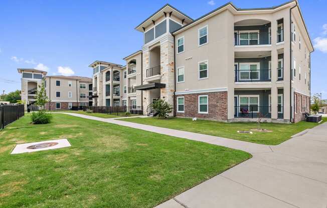 San Marcos, TX Apartments - Exterior View of Radiate Apartments Building Surrounded By Lush Landscaping