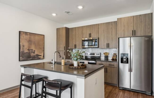 a kitchen with stainless steel appliances and a island with two chairs at Stella, San Tan Valley Arizona