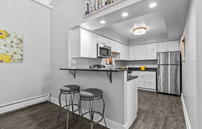a kitchen with white cabinets and a black counter top with two stools