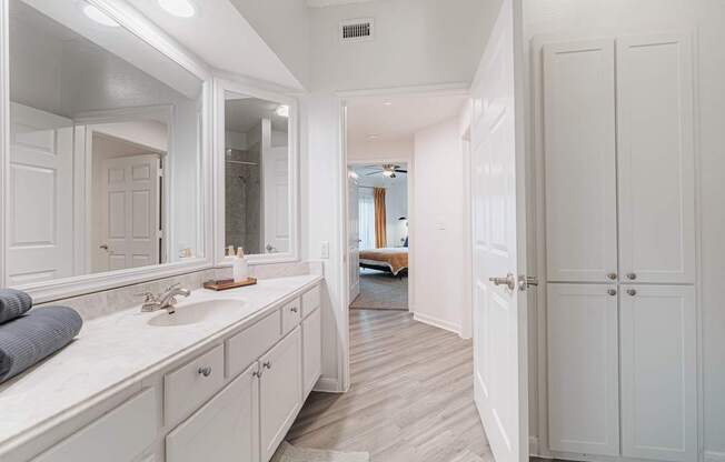A white bathroom with a vanity and a mirror.