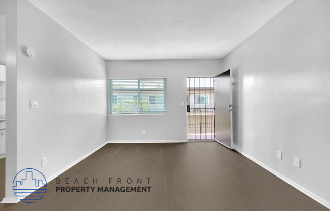 an empty living room with wood flooring and a door to a balcony