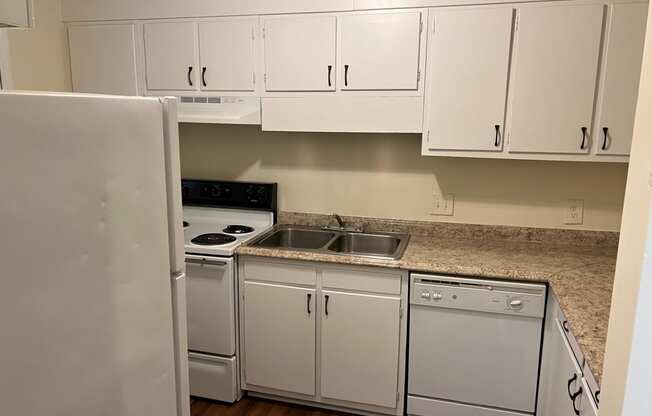 an empty kitchen with white appliances and white cabinets